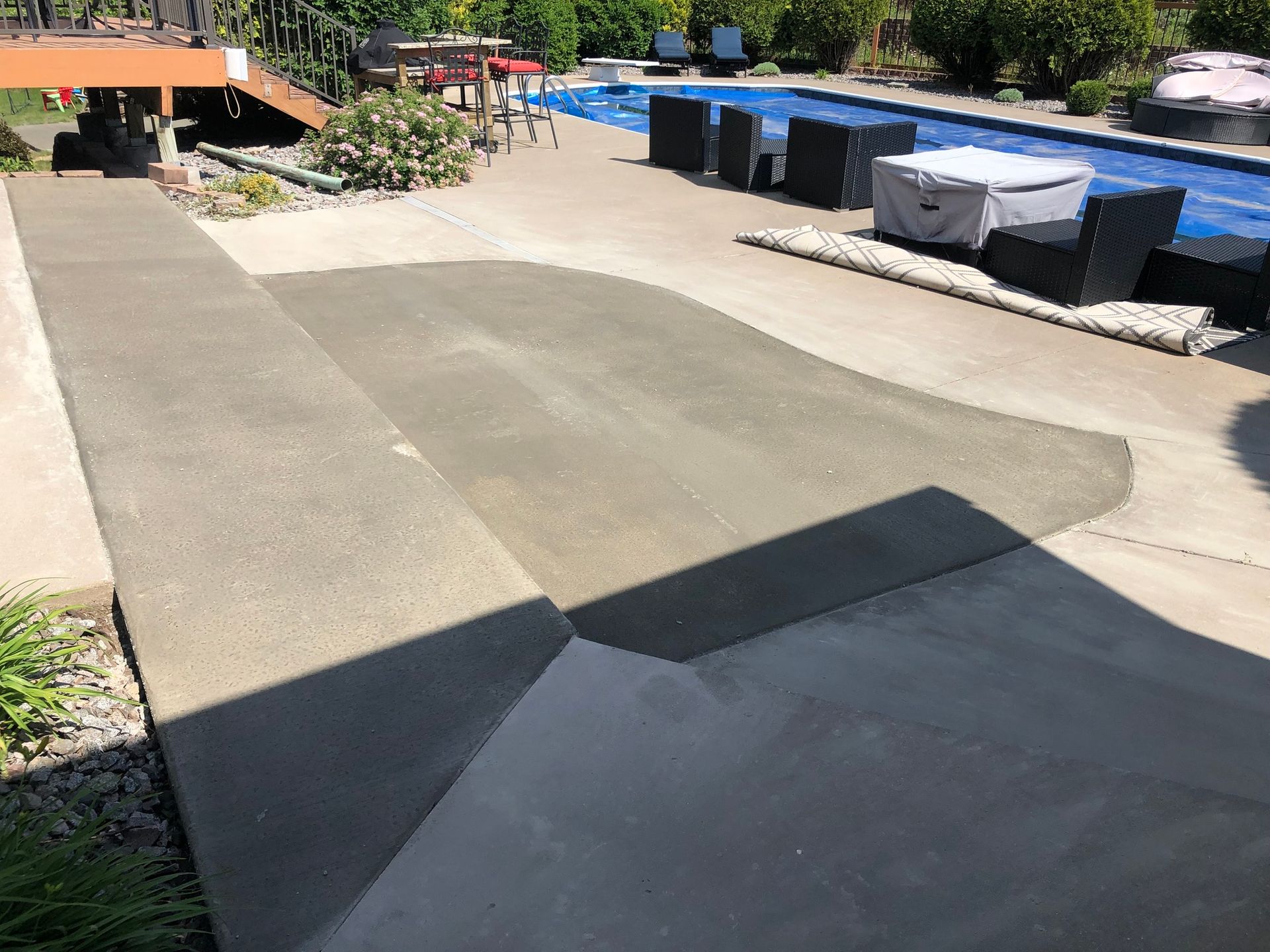 A concrete walkway leading to a swimming pool with chairs and umbrellas.