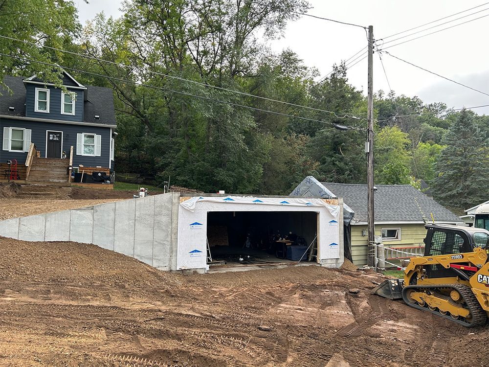 A house is being built on a hill next to a garage.