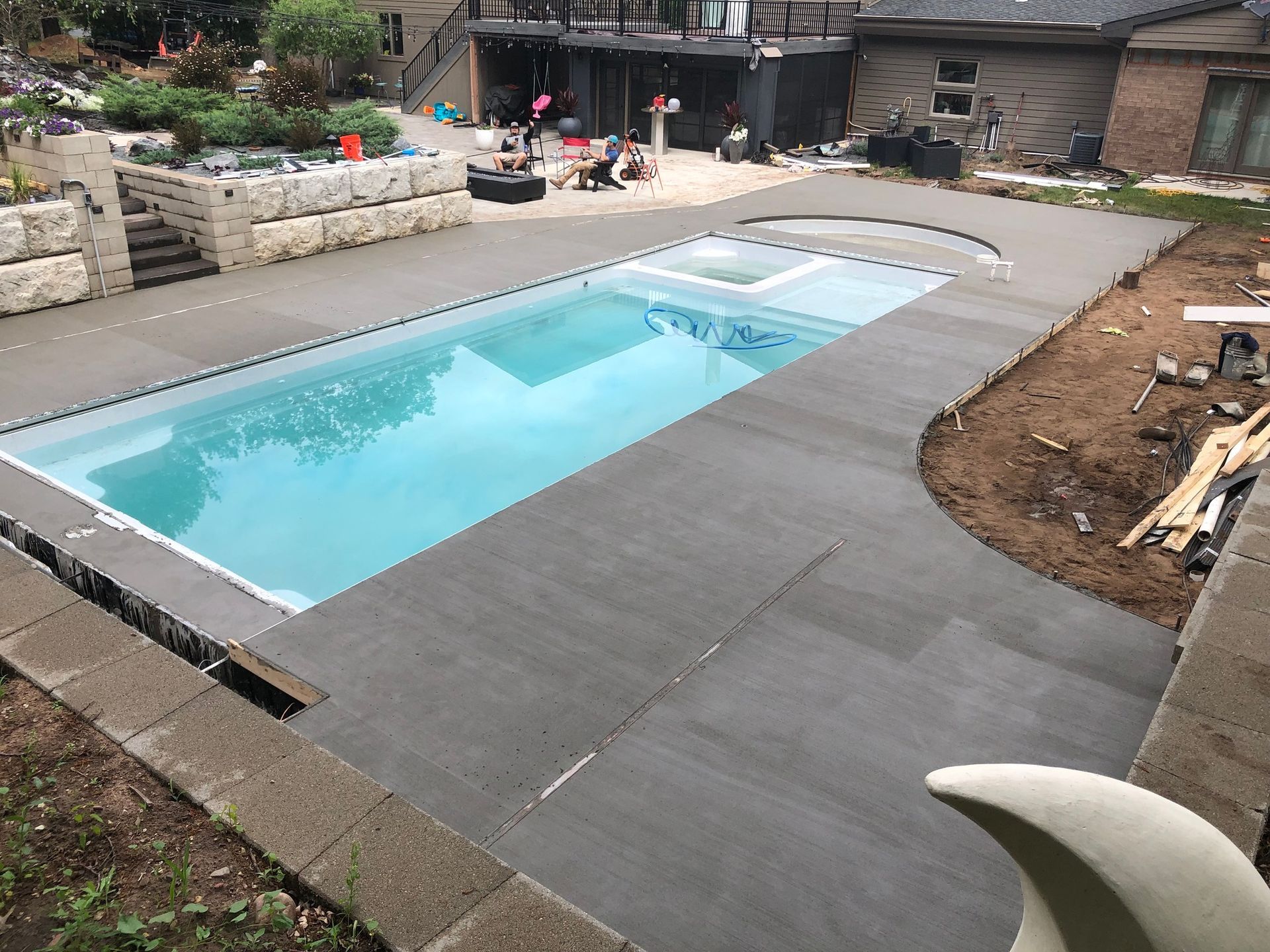 A large swimming pool is being built in the backyard of a house.