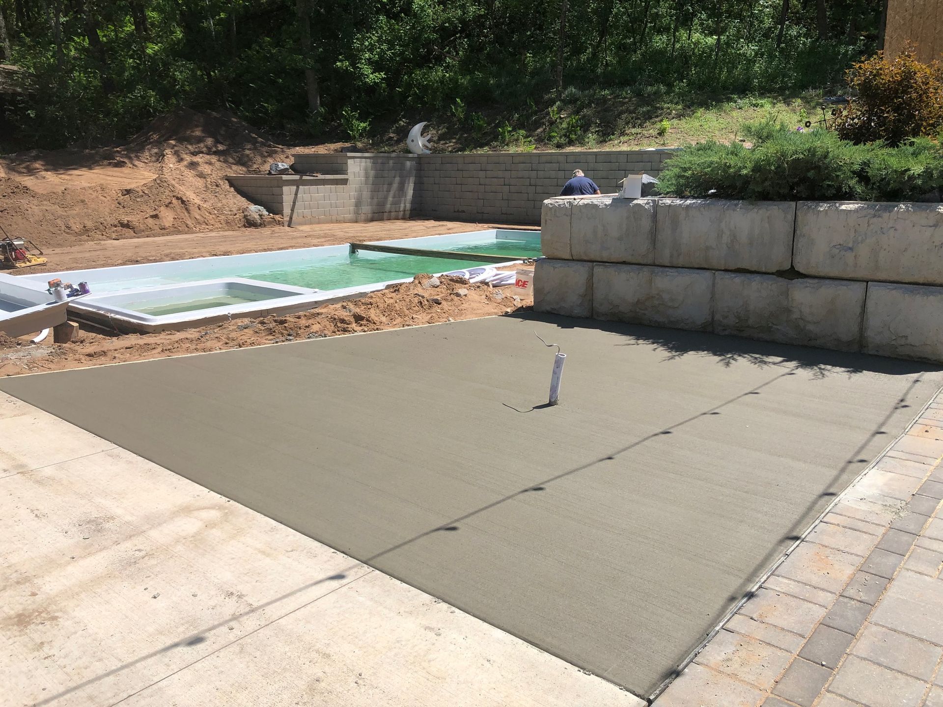 A concrete driveway is being built next to a swimming pool.