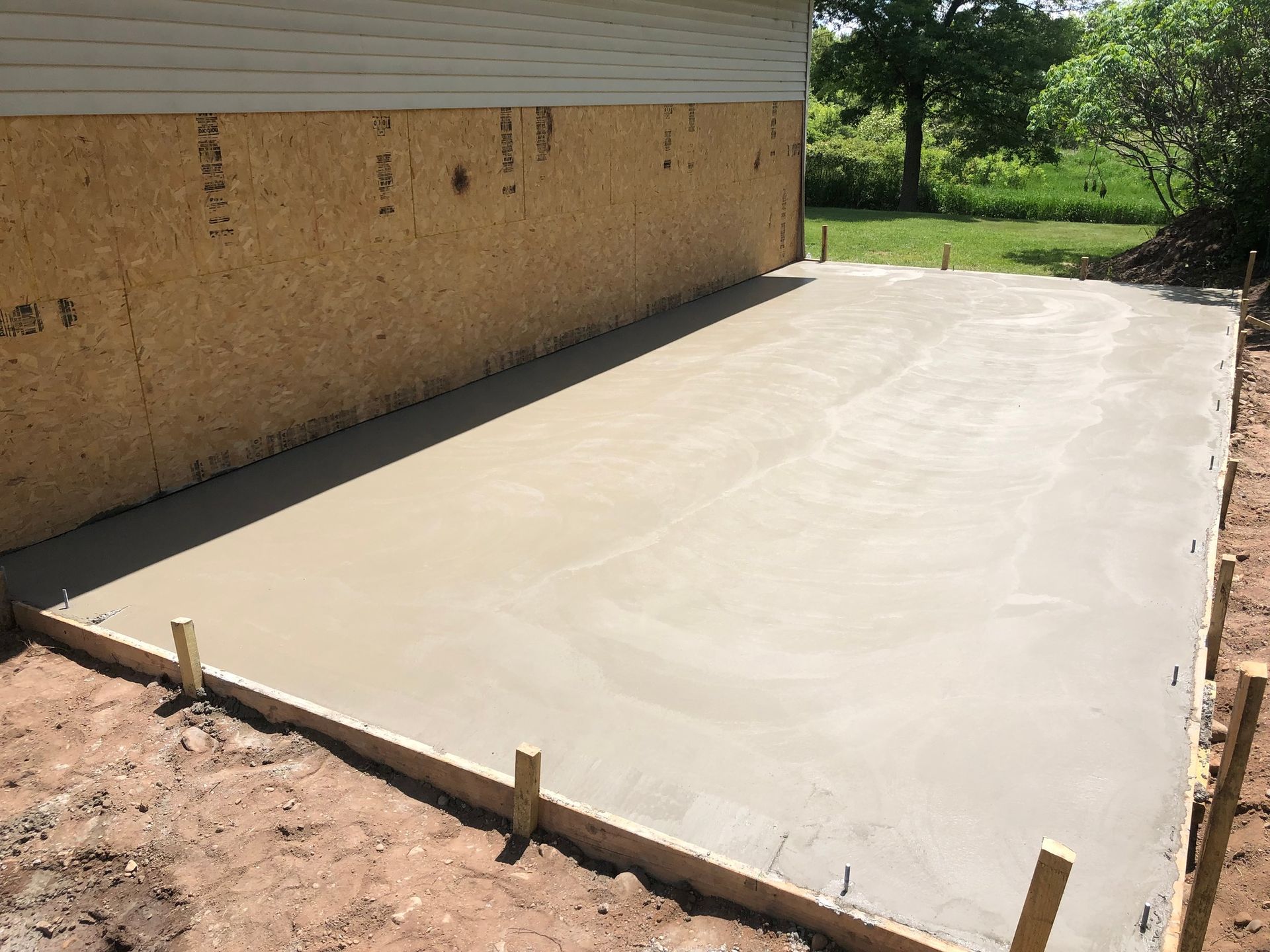 A concrete driveway is being built in front of a house.