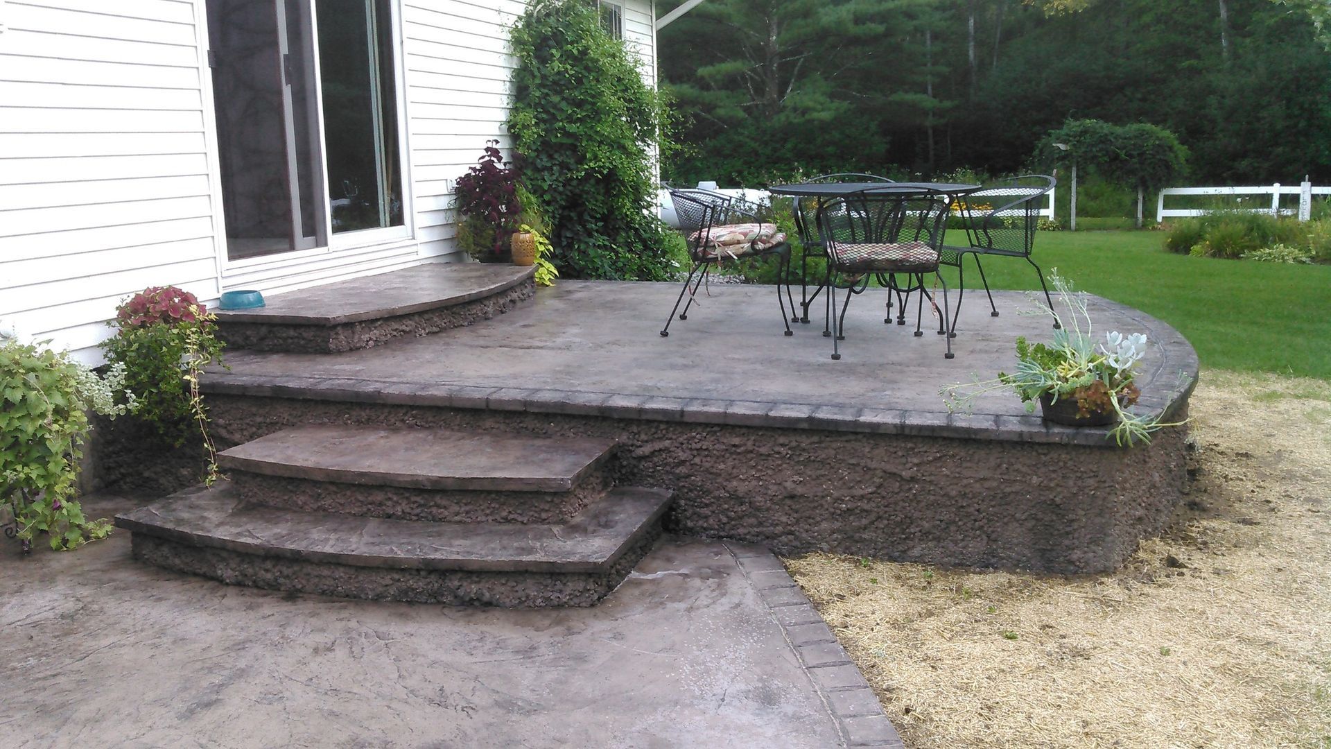 A patio with stairs and a table and chairs on it