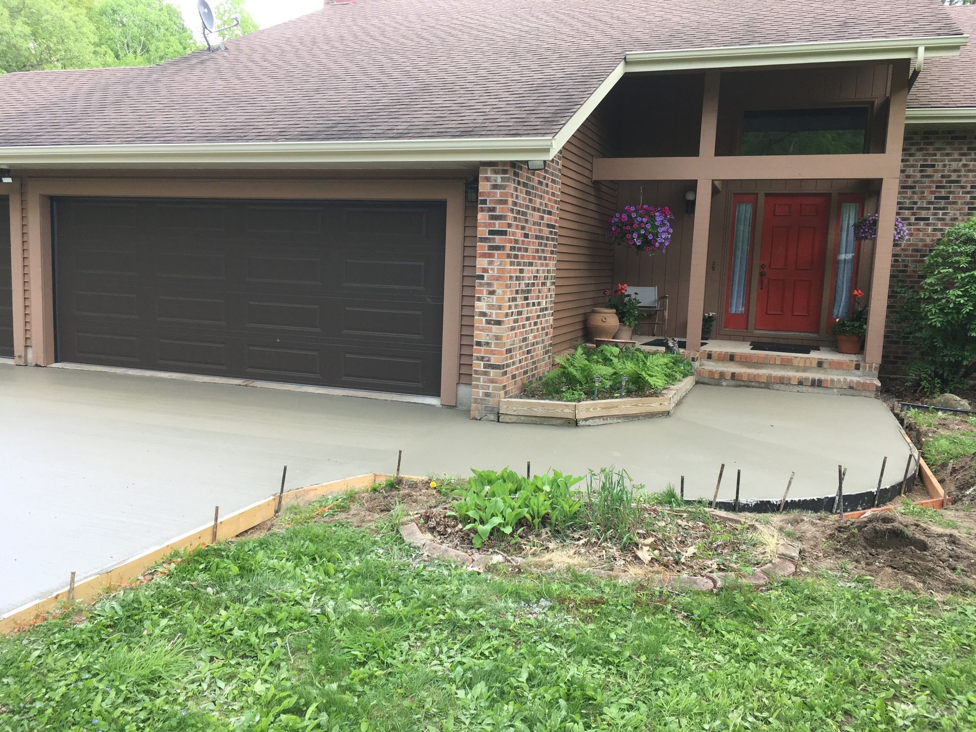 A house with two garage doors and a concrete driveway in front of it.