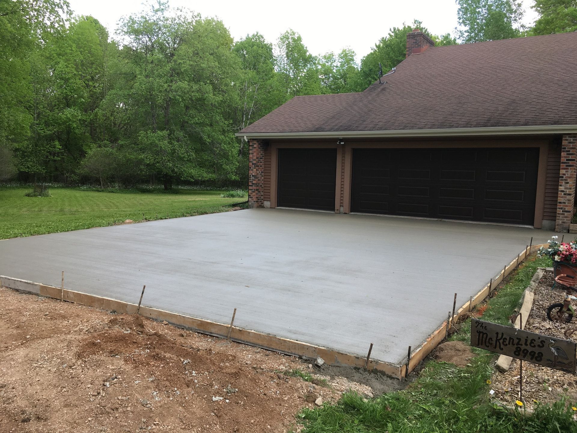 A concrete driveway is being built in front of a house