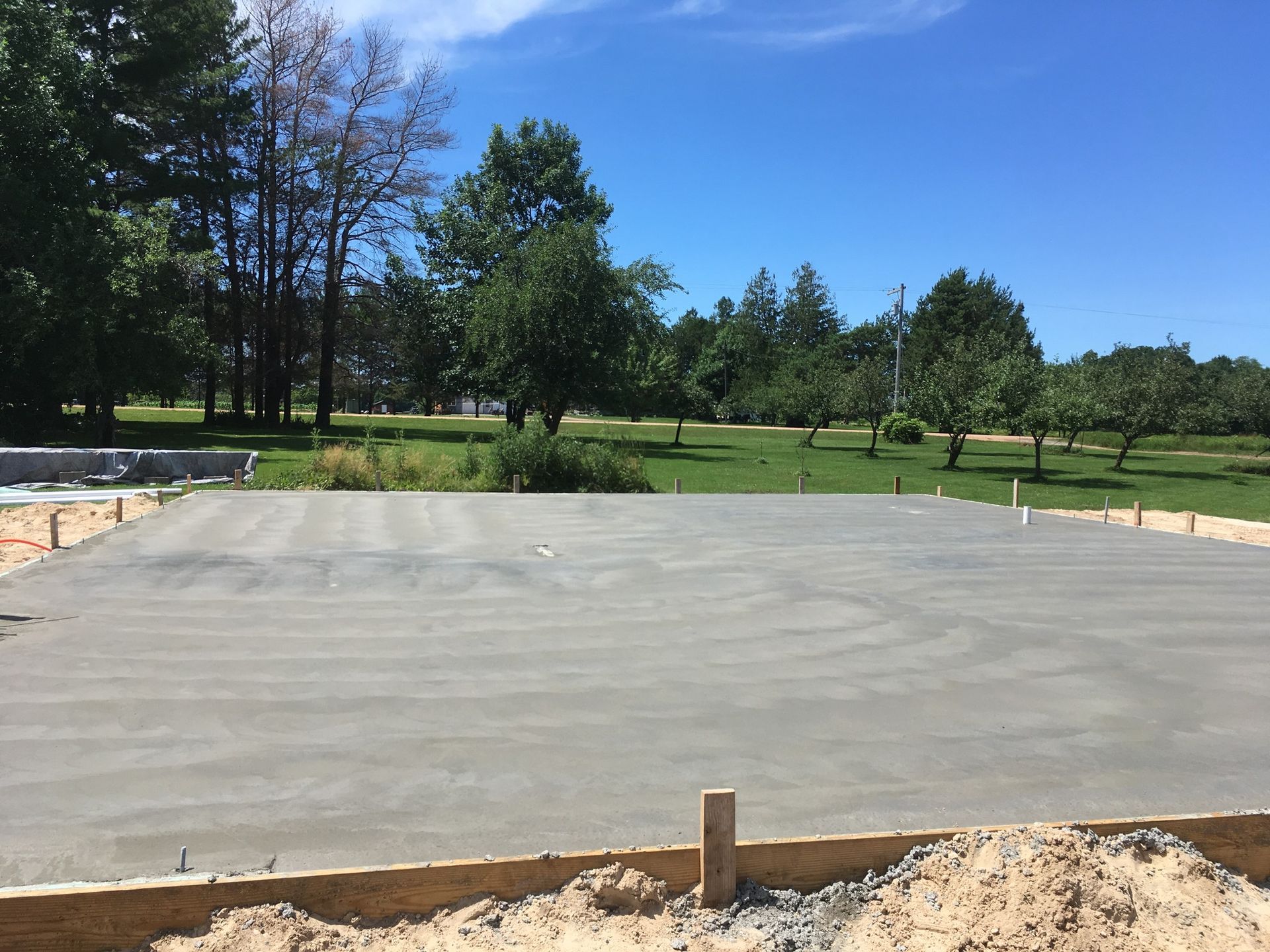 A concrete driveway is being built in a park with trees in the background.