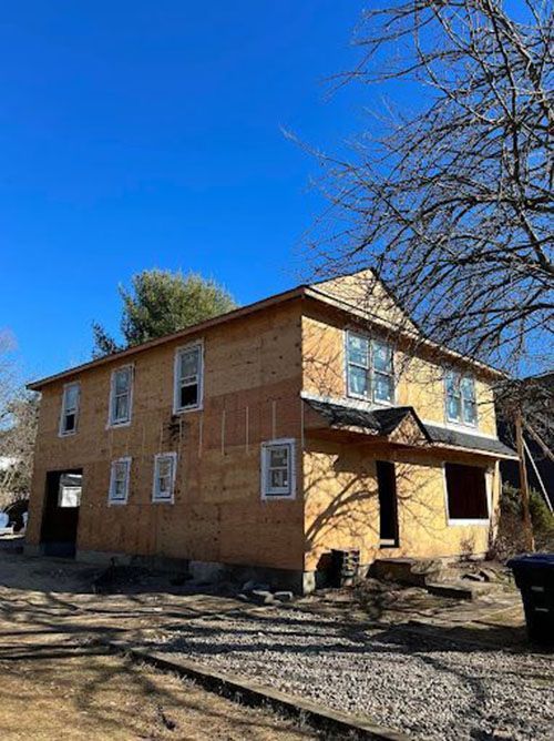 A house is being built with wood paneling and a blue sky in the background.