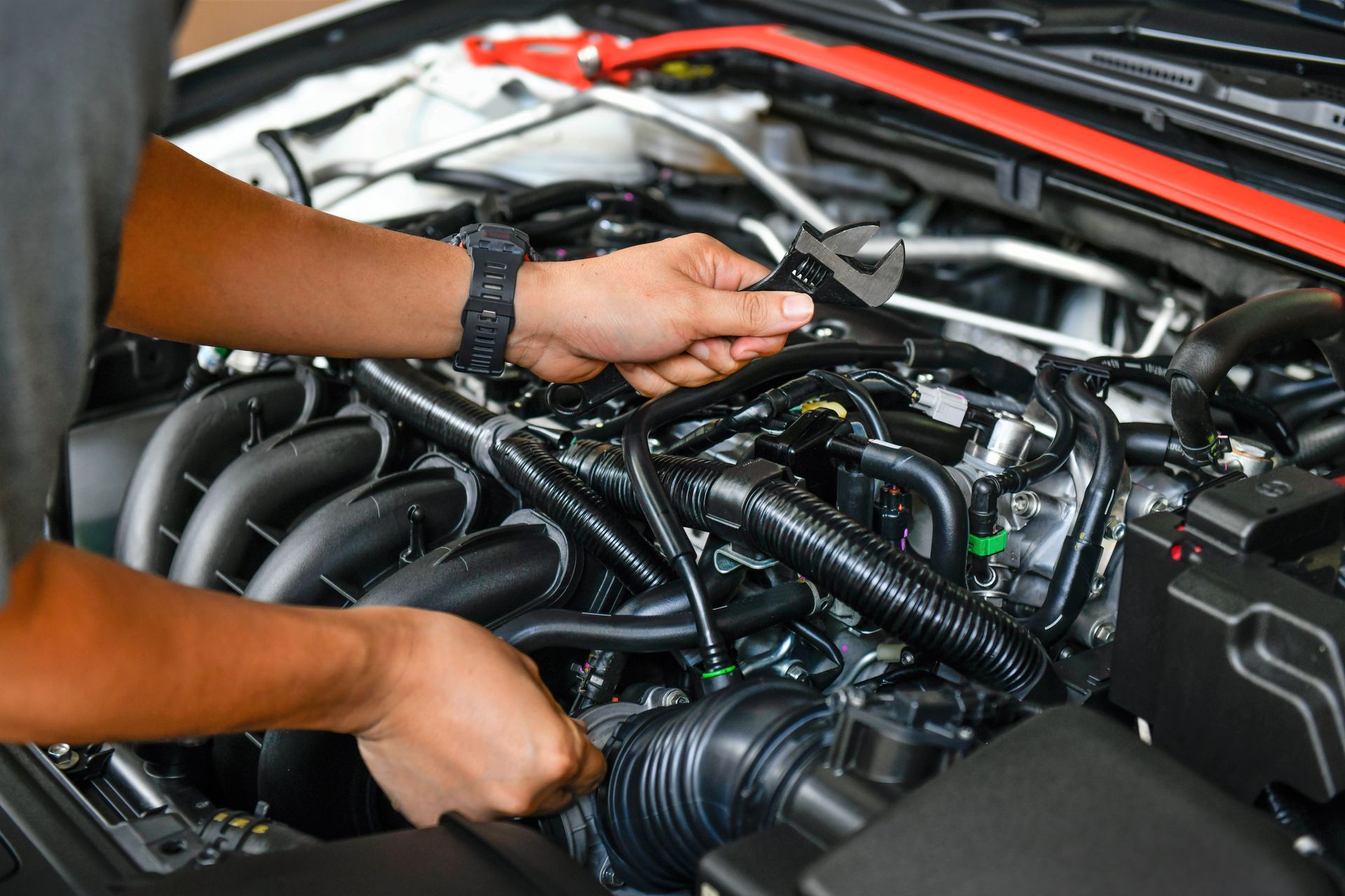Mechanic working on car engine, using a wrench.
