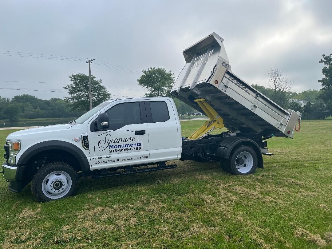 a white dump truck is parked in a grassy field