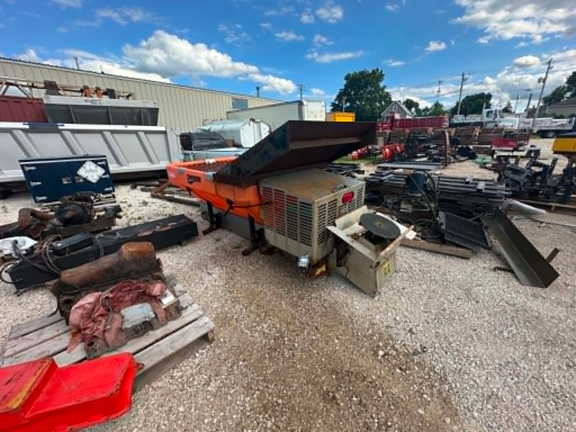 Junkyard with piles of scrap metal, machinery parts, and debris under a blue sky