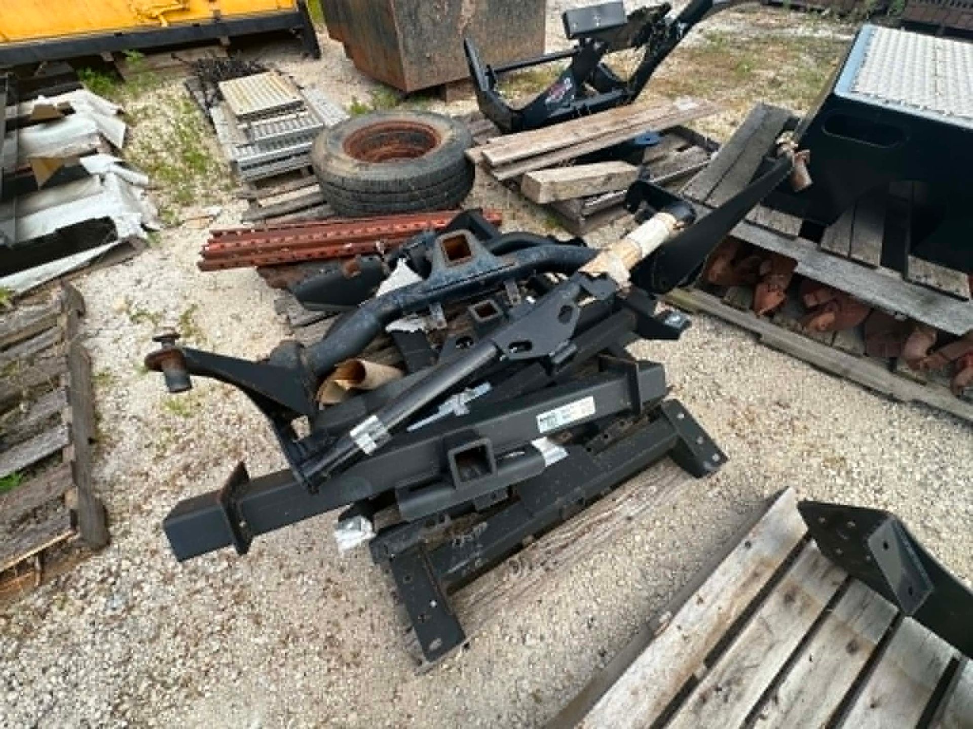 Black metal jack and parts piled in a cluttered outdoor yard with tires and scrap wood