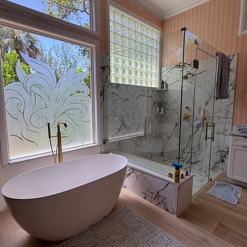 Modern bathroom with a freestanding tub, marble shower, frosted glass window, and wood floor