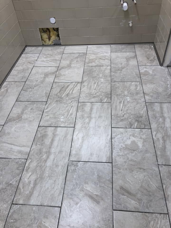 Tiled bathroom floor with gray stone-look tiles and beige wall tiles under construction