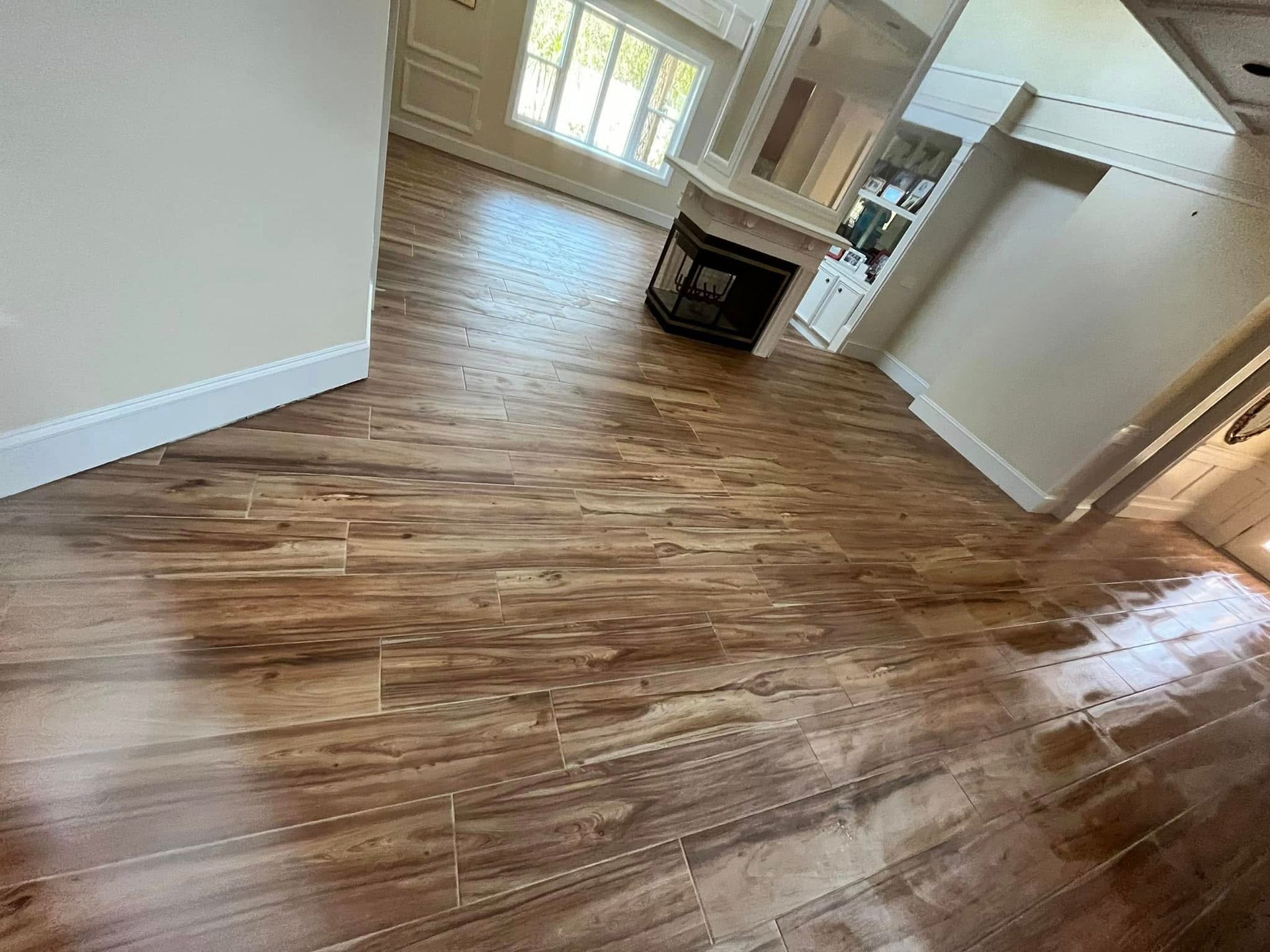 Vacant room with wood floors, white walls, kitchen island, and bright windows in the background