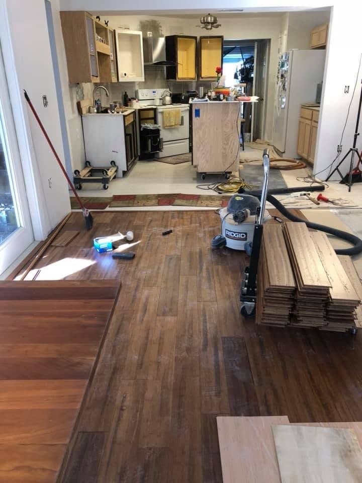 Partially renovated kitchen with new flooring, tools, and stacked wood in a home interior