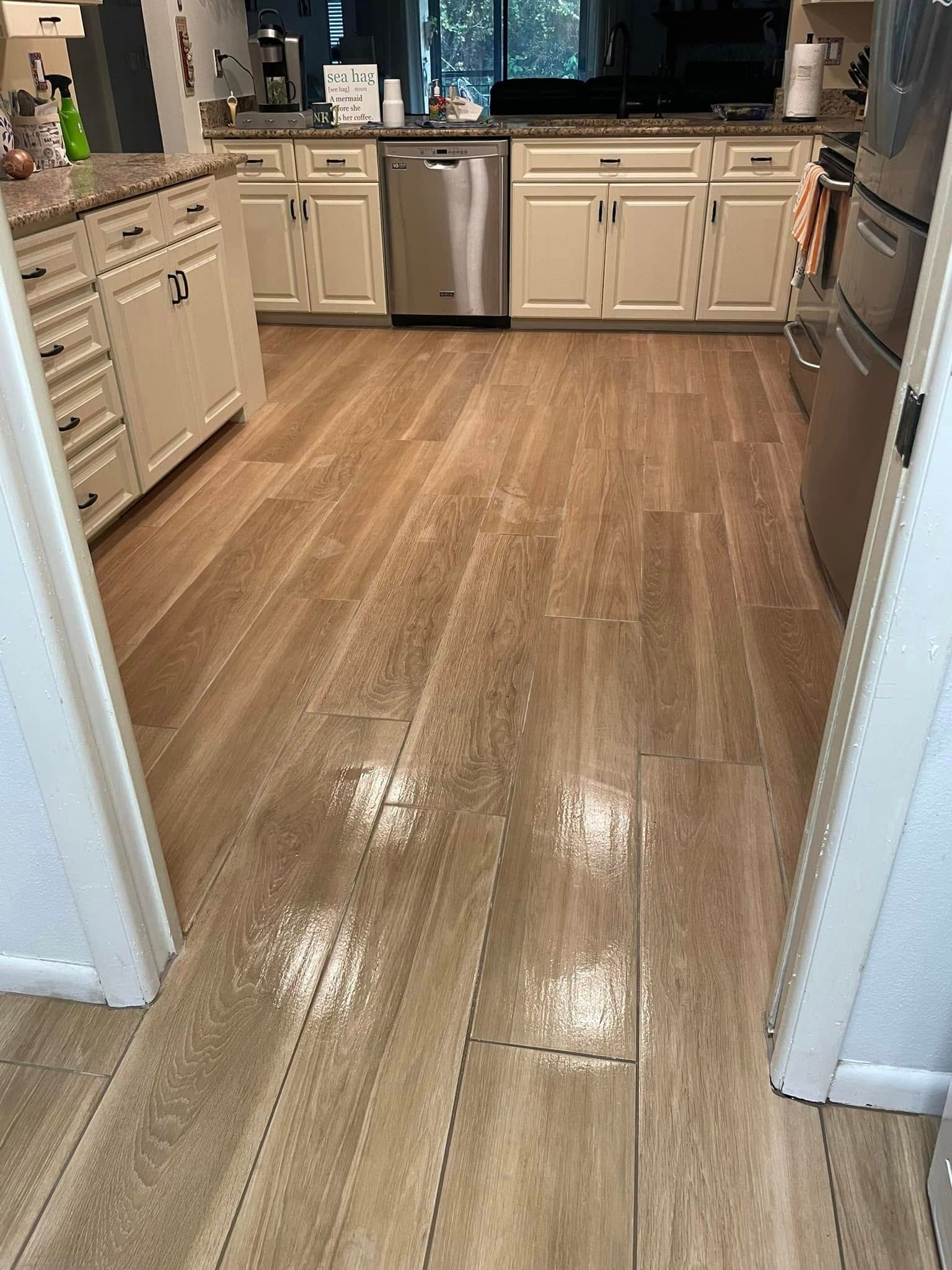 Kitchen with light cabinets, wood floor, and stainless steel appliances, viewed from a doorway.