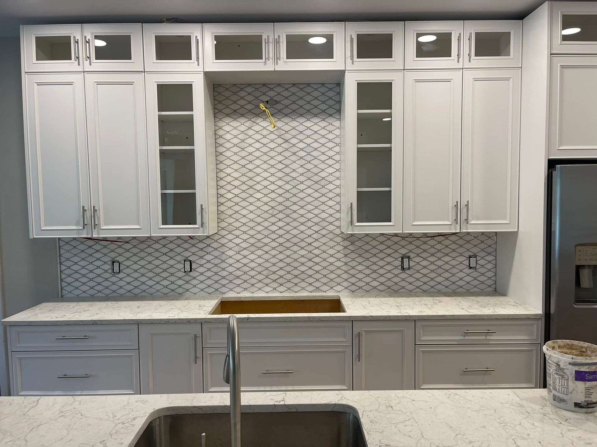 Modern white kitchen cabinets with mosaic tile backsplash and marble countertop