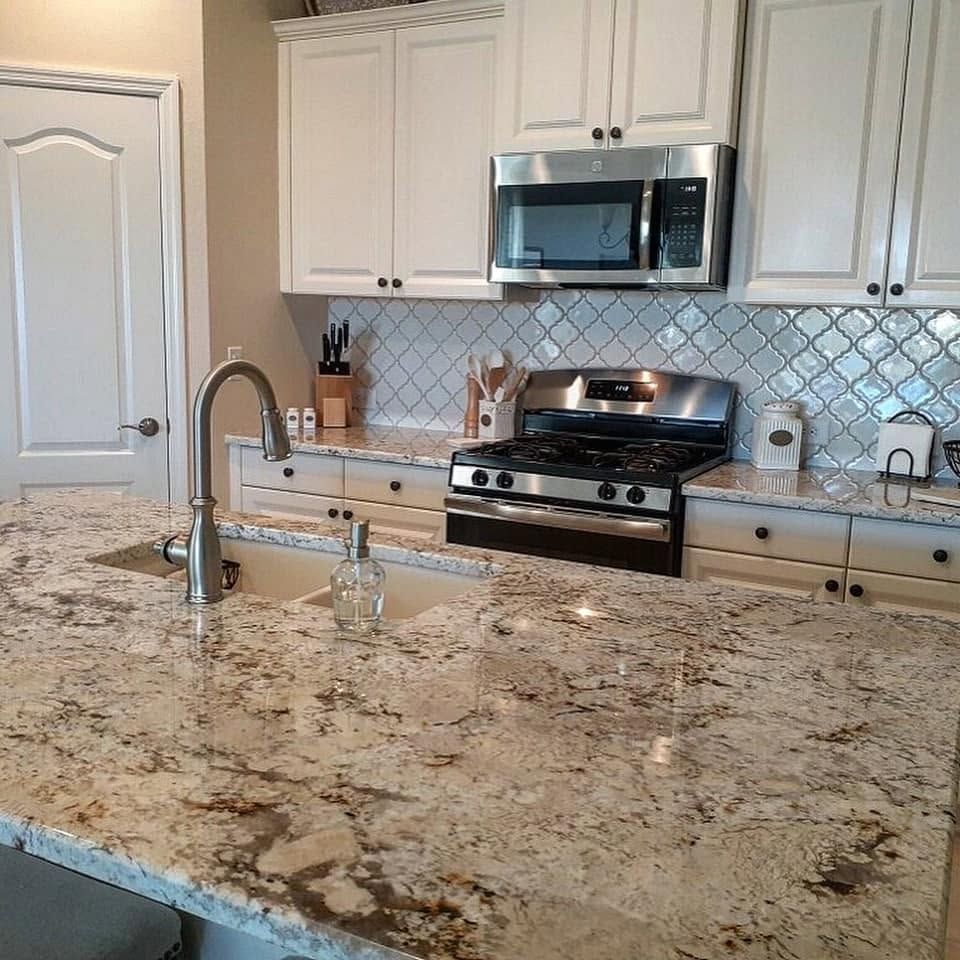 Modern kitchen with white cabinets, stainless steel appliances, and granite island countertop
