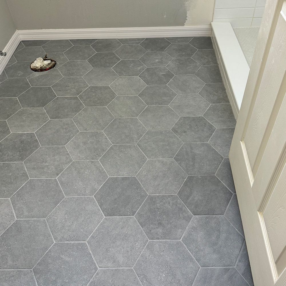 Small bathroom with gray hex tile floor and a toilet visible in the corner.