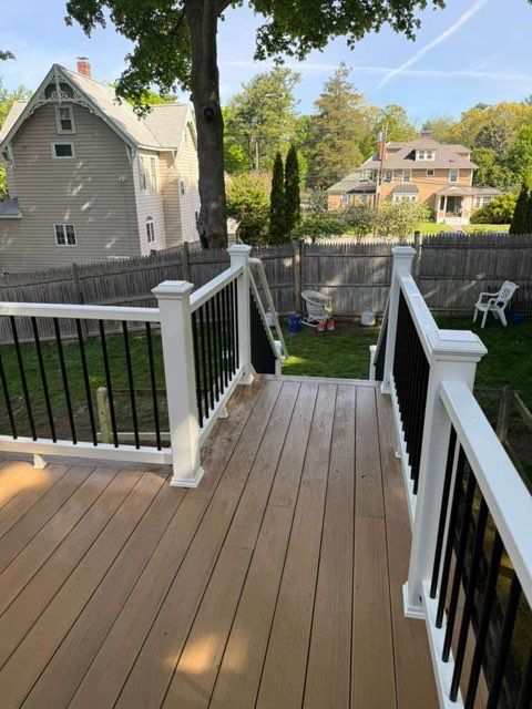 Back deck with black-and-white railings overlooking a fenced backyard and neighboring houses