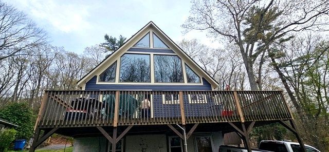 A-frame house with large windows and a wooden deck surrounded by trees