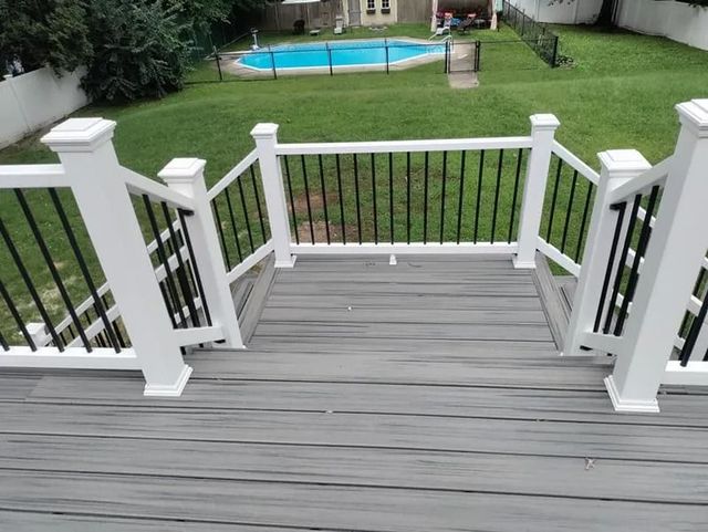 Grey deck with white railing and black spindles, looking out to a backyard with a pool.