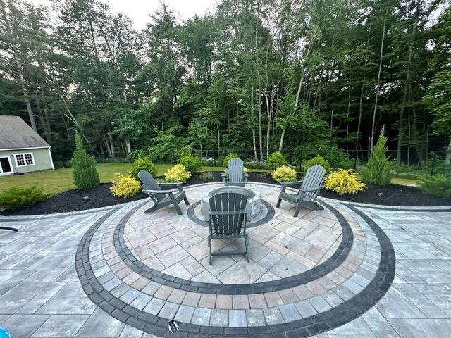 Circular paved patio with fire pit, surrounded by Adirondack chairs and landscaping.
