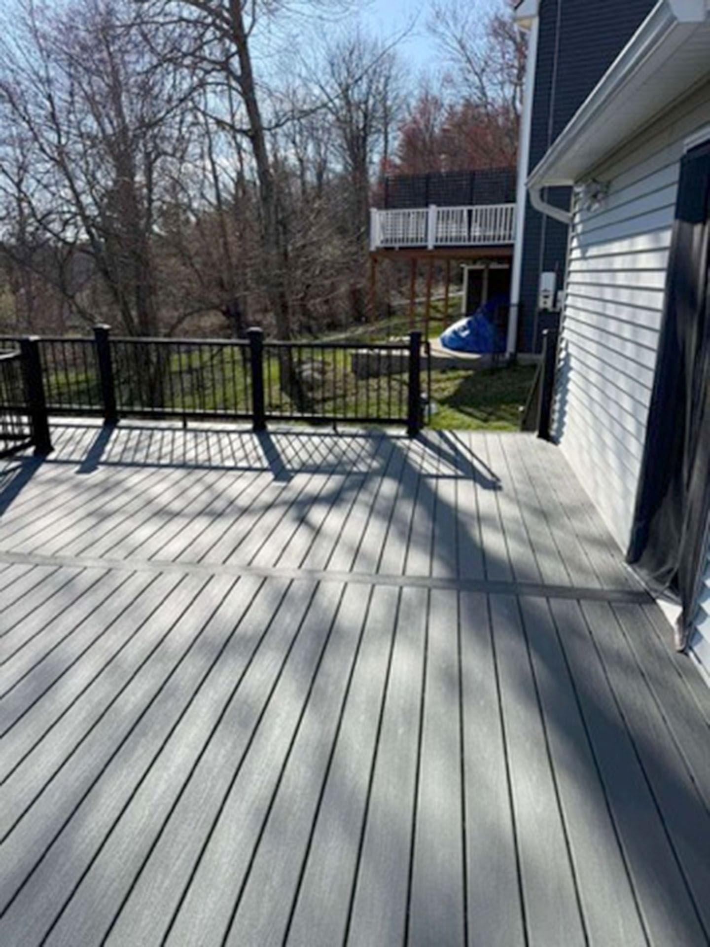 A wooden deck with gray boards and black railings