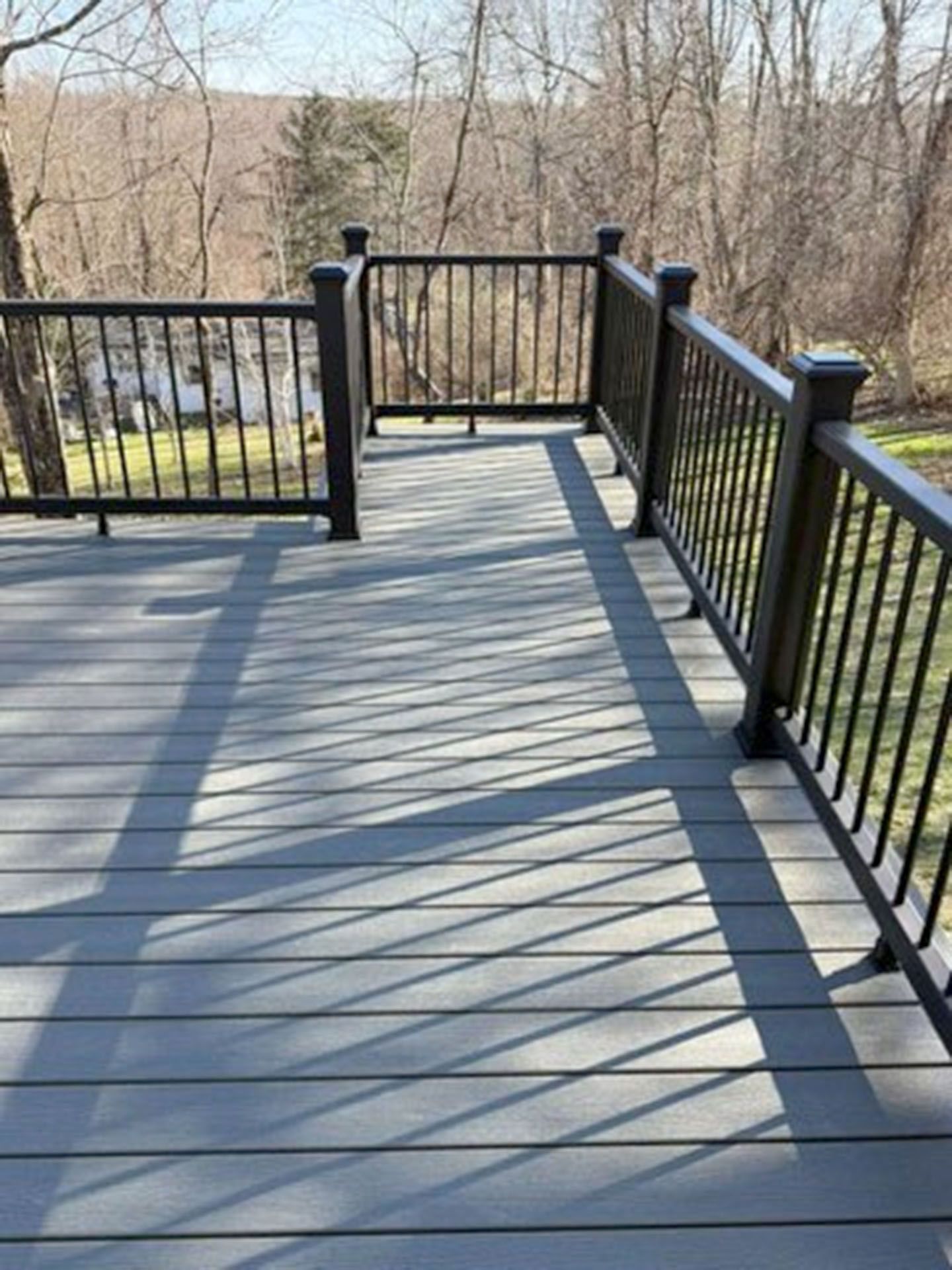 A gray composite deck with black metal railings