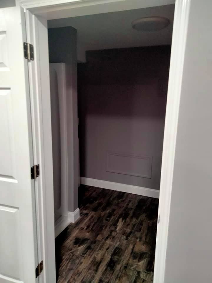 Open doorway into a room with gray walls, white trim, and wood-look flooring.
