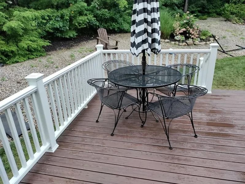 Deck with black and white striped umbrella, round table, and four metal chairs.