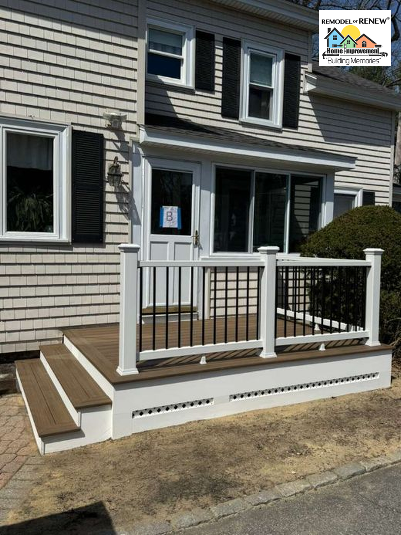 A tan house with a new wood-colored deck, white railings, and two steps leading to the front door.