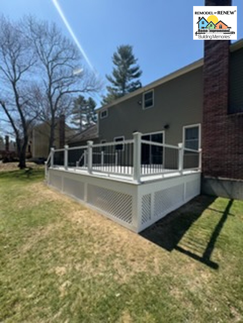 A newly built backyard deck featuring white railings, black balusters, and white lattice skirting on a sunny day.