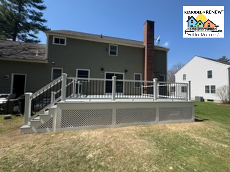 A newly built grey deck with white railings and lattice skirting attached to the rear of a two-story home.