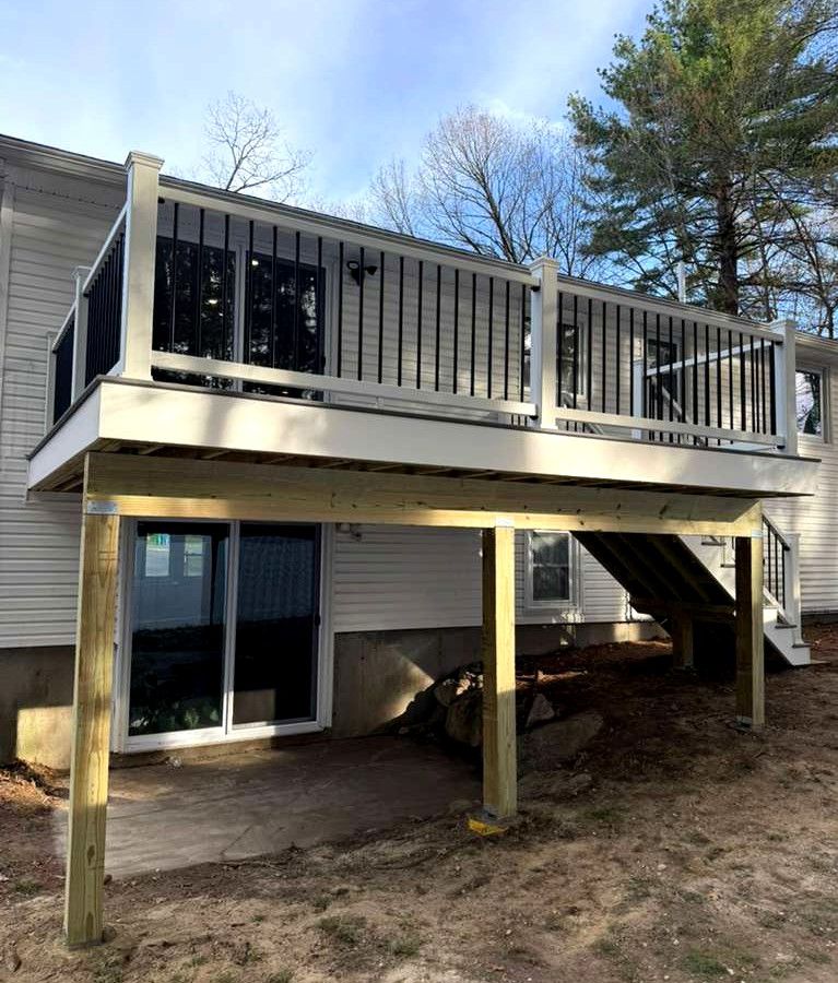 Raised wooden deck with stairs and railing attached to a house, viewed from below outdoors