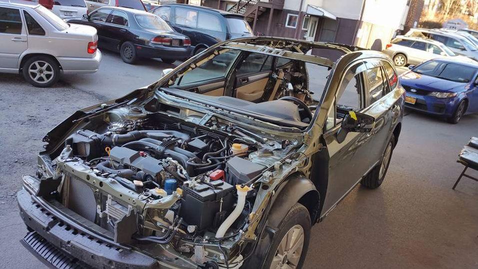 A car with the hood open is sitting in a parking lot.