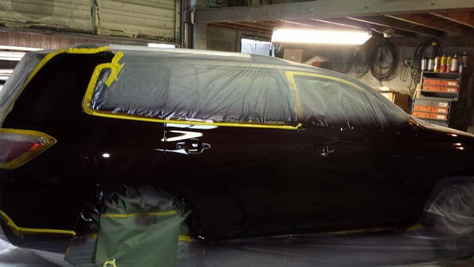 A car is being painted in a garage with yellow tape
