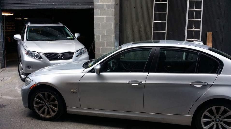 Two silver cars are parked next to each other in front of a garage.