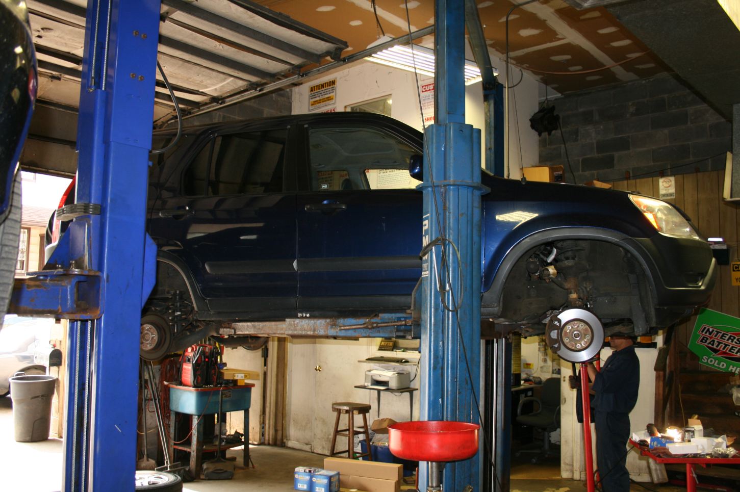 A blue suv is sitting on a lift in a garage