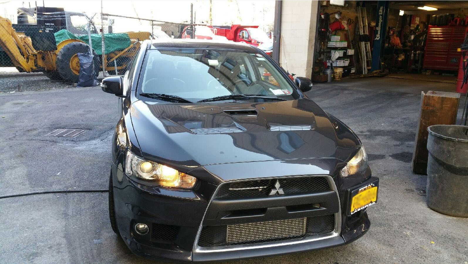 A black car with a yellow license plate is parked in a parking lot.