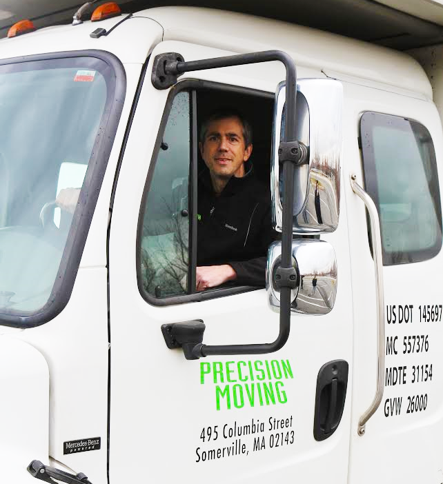 Man smiling in Precision Moving truck cab, Somerville, MA.