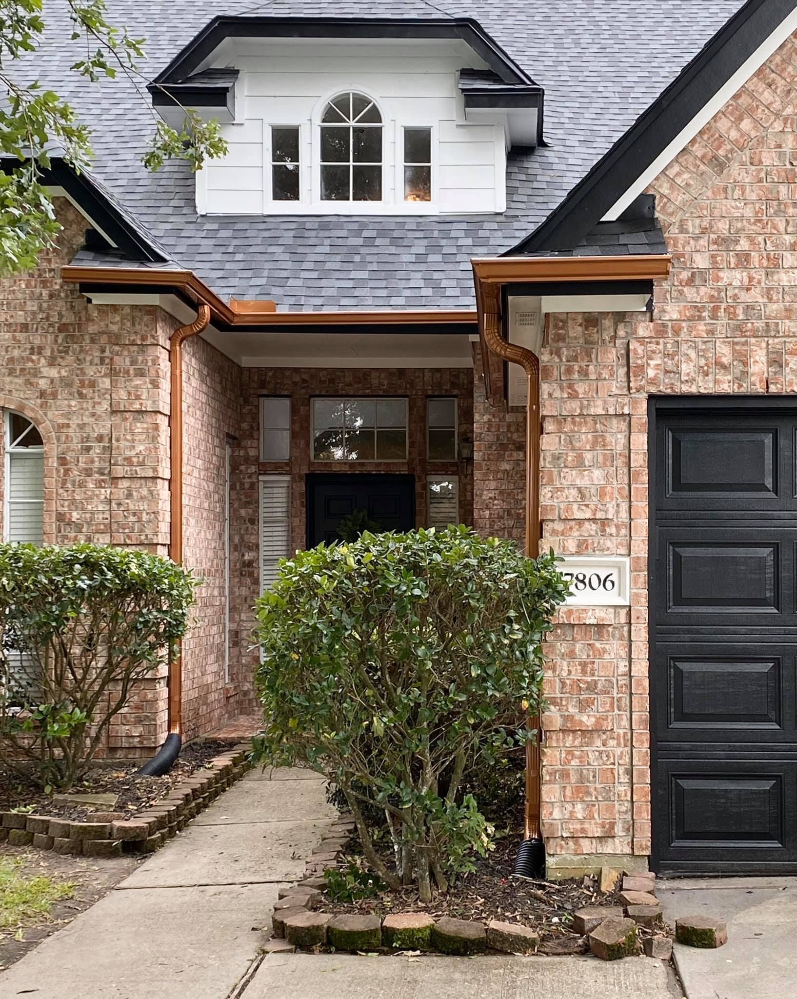 The front of a brick house with a black garage door.