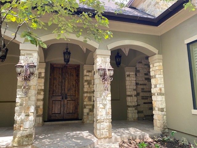 The front of a house with stone pillars and a wooden door.
