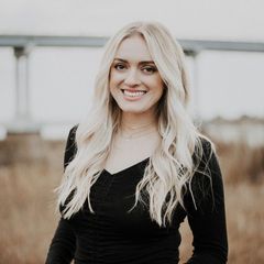 The woman is wearing a black shirt and smiling for the camera.