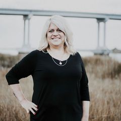 A woman in a black shirt is standing in a field with her hands on her hips