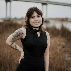 A woman in a black dress has a tattoo on her arm