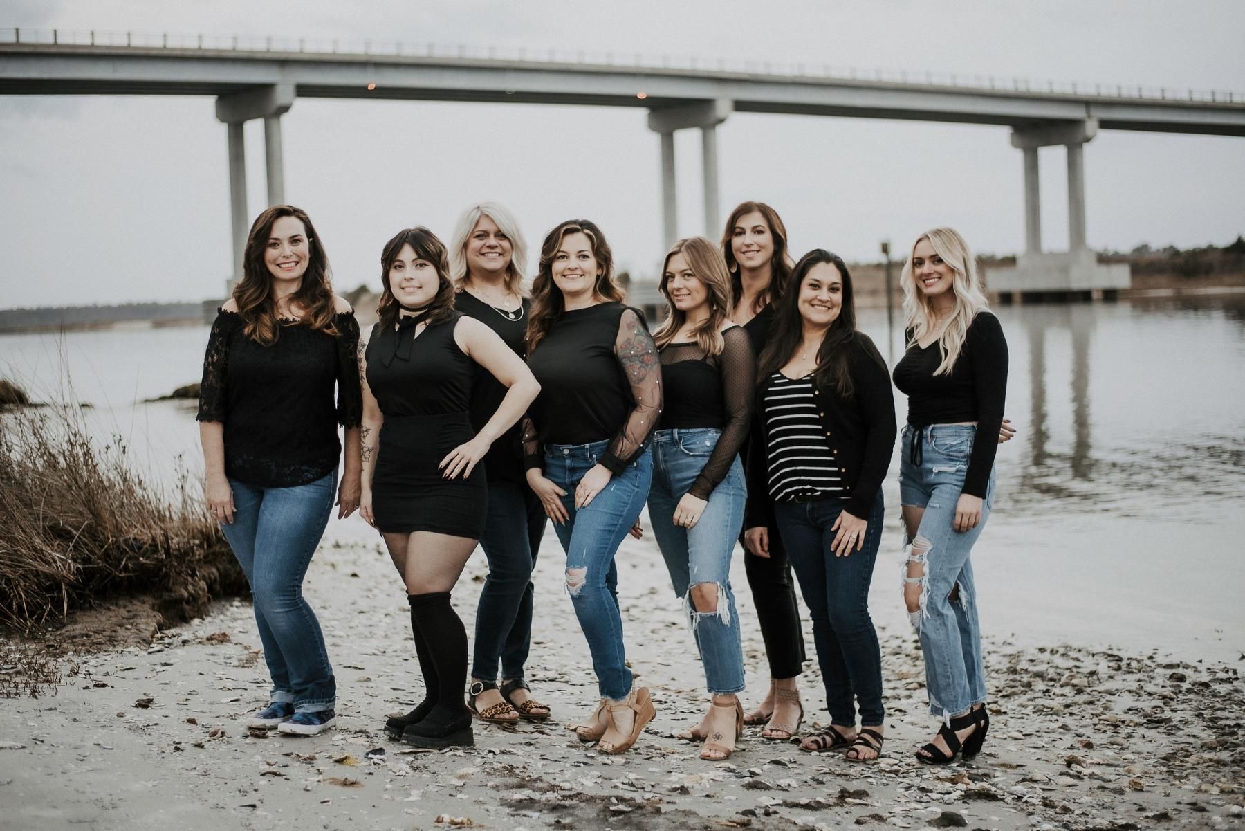 A group of women are posing for a picture in front of a bridge.