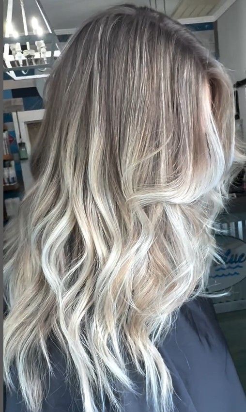 A woman with long blonde hair is sitting in a chair in a salon.