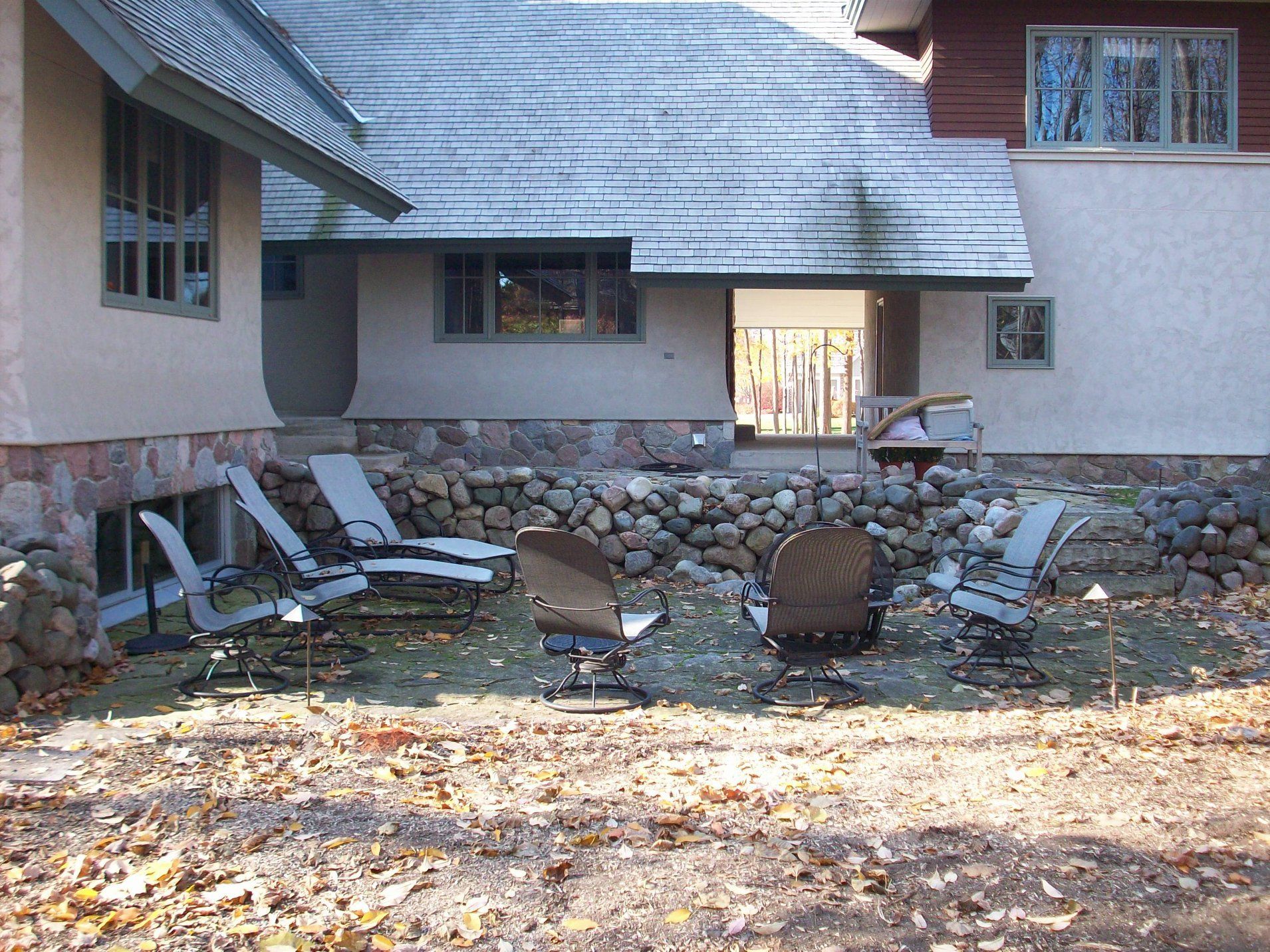 A patio with chairs and a fire pit in front of a house
