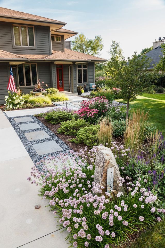 A large house with a lush green yard and flowers in front of it.