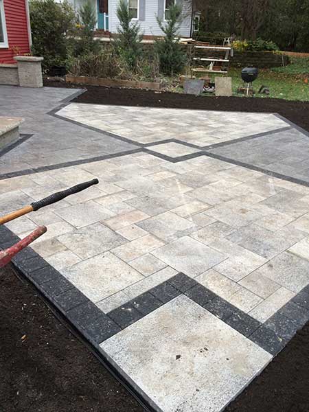 A patio with a rake and shovel on it in front of a house.